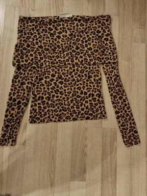 Leopardmönstrad offshoulder topp Kappahl - Säljer en snygg offshoulder topp från Kappahl i storlek XS. Toppen har leopardmönster i bruna och svarta toner. Jätte fint skick, andvänt några få gånger.