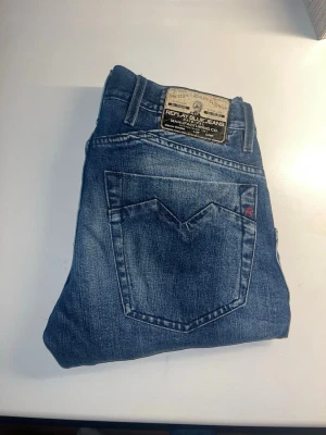 Replay jeans - Säljer ett par Replay Skar jeans i klassisk blå tvätt med snygga slitningar och raka ben. Materialet är robust denim i bomull, perfekt för dig som gillar street och casual. Midja 39cm, längd 103cm. JAG SKICKAR EJ FLER BILDER NÄR JAG BÄR JEANSEN! för storleksguide hänvisar jag till måtten och för bättre inblick i passformen rekommenderar jag att googla på modellnamnet. kolla måtten noggrant :) s5,1