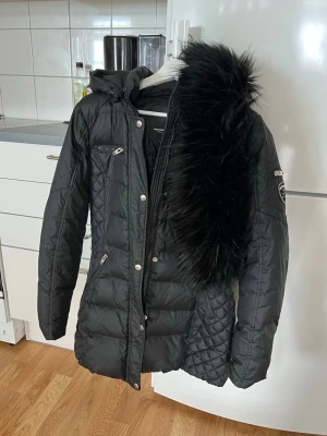 rockandblue dunjacka - Storlek 40 (lite mindre i storleken, skulle säga att den är mellan 38-40 i storlek)  Färgen är svart och luvan är avtagen så den får man sätta dit själv om man vill.   Jackan är använd fåtal gånger under 2 vinter säsonger. Det finns inga hål, revor eller slit på jackan.   Nypris 3799:- köpt från Bubbleroom.