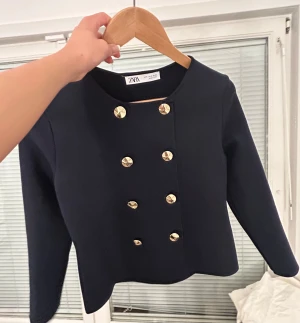 Mörkblå oanvänd skepparkavaj från Zara - Snygg mörkblå skepparkavaj från Zara med guldiga knappar framtill. Jackan har en rak och kortare passform, rund halsringning och långa ärmar. Perfekt för dig som gillar klassisk stil med en modern twist. Aldrig använd. Pris diskuterbart❤️