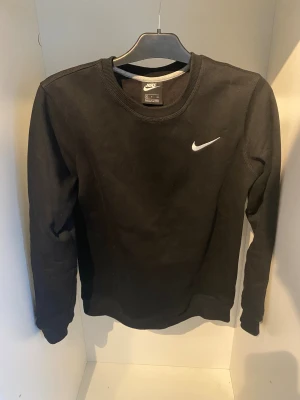 Nike Sweatshirt - Svart crewneck sweatshirt från Nike med klassisk vit logga på bröstet. Tröjan har rund hals, ribbade muddar och är tillverkad i mjuk bomullsmix. Perfekt för chill eller sportiga dagar. Enkel och stilren design som funkar till allt.                                                               Obs den är en (Rep)