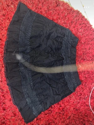 Svart kortkjol med spetsdetaljer - Säljer en svart kortkjol med breda spetsdetaljer och volang längs nederkanten. Kjolen har en luftig och lätt struktur, perfekt för dig som gillar en chill och feminin stil. Materialet känns som bomull och spetsen ger extra vibe till outfiten.