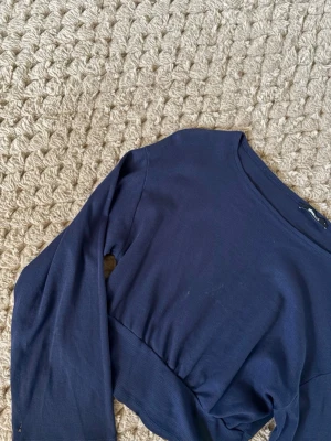 Mörkblå croppad topp Gina Tricot - Säljer en mörkblå croppad topp från Gina Tricot i storlek S. Toppen har långa ärmar och är tillverkad i ett ribbat material som ger en snygg struktur. Enkel och stilren design med rund halsringning, perfekt att matcha med jeans eller kjol.