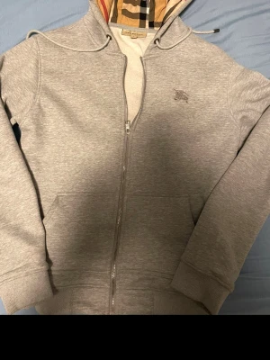 Burberry zip hoodie –  mycket fint skick - Säljer en Burberry zip-up hoodie i mycket fint skick. Klassisk design med hög kvalitet och bekväm passform. Dragkedja framtill och huva – perfekt för både vardag och stilren look.
