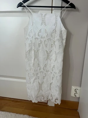 Vit spetsklänning med smala axelband XS - Superfin vit kortklänning med smala axelband och vackert spetsmönster. Klänningen har dragkedja i sidan och fodrad insida. Helt ny💖