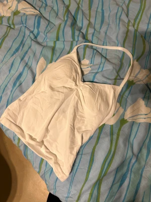 Sporttopp - snygg linnetopp i vit färg med halterneck och lätt rynk vid bysten. Aldrig använda endast testade