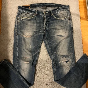 Dondup jeans med slitningar - Tjena! Säljer nu min exklusiva och Snygga blå jeans från Dondup med slitna detaljer och revor framtill. Jeansen har klassisk femficksdesign, kontrastsömmar och en något tvättad look. Tillverkade i Italien och gjorda i jeansmaterial. Perfekta för en avslappnad streetstil. Finns ett lagat hål som syns på bild 4 annars inga defekter. Skriv vid funderingar 
