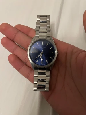 Studgaard klocka - Snygg klocka från stuggard med stilren blå urtavla och datumvisning. Armbandet är i silverfärgat rostfritt stål med klassisk länkdesign. Perfekt accessoar för dig som gillar en clean och modern look. Extra länkar medföljer för justering av storlek. Kommer utan box men kommer med extra band