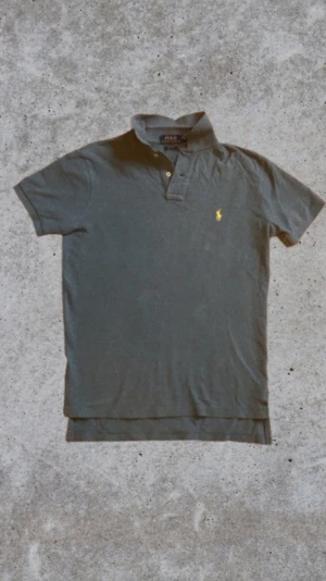 Mörkblå pikétröja från Ralph Lauren -  Polo Ralph Lauren piké – blå med gul logga (S)  Säljer en klassisk blå Polo Ralph Lauren-piké i storlek Small. • Färg: Marinblå • Logga: Gul broderad polo-ryttare • Storlek: S • Passform: Slim/regular (ange gärna om du vet) • Skick: Mycket fint skick – väl omhändertagen • Material: Mjuk och bekväm bomull  Perfekt basplagg som funkar året runt. Skriv om du vill ha mått eller fler bilder! 💙✨
