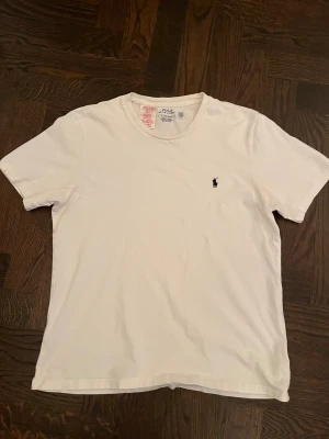 Vit Ralph Lauren T-shirt - Snygg Ralph Lauren T-shirt i mycket bra skick. Vit med blå logga. Storlek S. Orginal pris 899kr. 