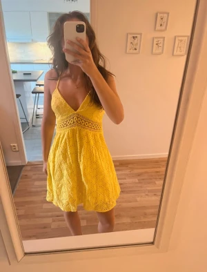 Gul klänning - Klänningen har knyte i ryggen som man sjölv kan justera samt vaddering i bysten. Den är i en fin gul färg och har ett fint vroderat mönster.