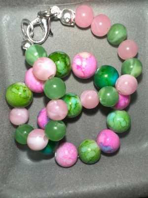 Färgglatt pärlarmband med karbinlås - Namn ”green.pink artikelnummer ”84WQ” 18/19cm Säljer ett snyggt armband med runda pärlor i rosa, grönt och marmoreringar. Pärlorna är av glas och har en cool mix av pastellfärger. Armbandet har ett silverfärgat karbinlås som gör det enkelt att ta av och på.