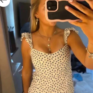 Vit prickig sommartopp från H&M - Supersöt vit sommartopp från H&M med mörkblå prickar och volangaxelband. Toppen har en feminin och somrig känsla, perfekt till varma dagar. Materialet känns lätt och luftigt.🩷🩷🩷