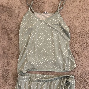 Prickigt linneset från Happy Holly Bubbleroom - Söt ljusgrönt set från Happy Holly Bubbleroom med vita prickar. Toppen har v-ringning och är tillverkad i mjuk polyester, perfekt för varma dagar eller som mysig pyjamasdel. Kjolen har en enkel och stilren design som känns fräsch och ungdomlig.