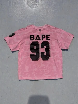 Pink Bape Jersey - I’m selling a pink Bape jersey that has barely been used, as it’s too big for me. It’s in great condition and perfect for any style — especially for a casual summer look. Feel free to message me for measurements or if you have any questions!