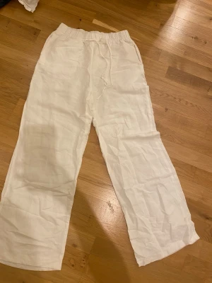 Vita linnebyxor från H&M XS - Säljer ett par vita linnebyxor från H&M i storlek XS. Byxorna har resårmidja med snörning och raka ben för en chill och luftig vibe. Perfekta till sommaren och lätta att matcha med allt. Materialet är en skön linneblandning.