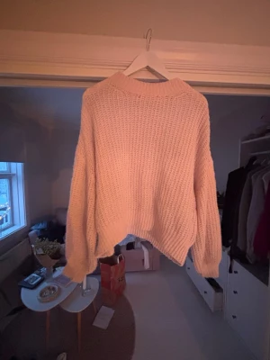 Rosa stickad tröja med loose fit - Säljer en mysig ljusrosa stickad tröja med loose passform och långärmade ärmar. Tröjan har en grovstickad struktur och ribbad kant vid hals, ärmslut och nederkant. Perfekt för kyliga dagar och enkel att matcha med jeans eller kjol.