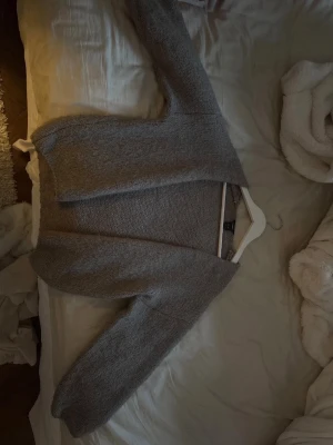 ‼️RESARVERAD‼️ - Mysig grå stickad kofta från H&M med lång ärm och enkel, öppen design utan knappar. Perfekt att slänga över en topp för extra värme. Koftan har en mjuk känsla och är lätt att matcha med olika outfits.
