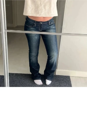 Mörkblå bootcut jeans låg midja - Säljer ett par mörkblå jeans med snygg tvätt och lätt slitna detaljer. Modellen har låg midja och bootcut-ben. Säljer då de inte längre kommer till användning. Innerbenslängs ca 86 och midjemått ca 40 🫶🏼 (lånade bilder skriv för fler bilder på)