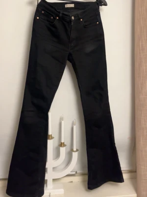 Svarta bootcut jeans från Perfect Jeans - Säljer ett par svarta bootcut jeans från Perfect Jeans i storlek 38. Jeansen har klassisk femficksdesign, hög midja och är tillverkade i ett stretchigt jeansmaterial. Snygg passform med utsvängda ben som ger en retrovibe.
