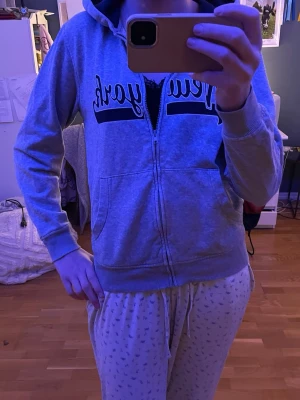 grå hoodie. - grå hoodie med tryck ”new york.” mörkblå i luvan och större i storlek, jag brukar ha storlek s/xs och passar mig bra och tillräckligt lång i armarna.