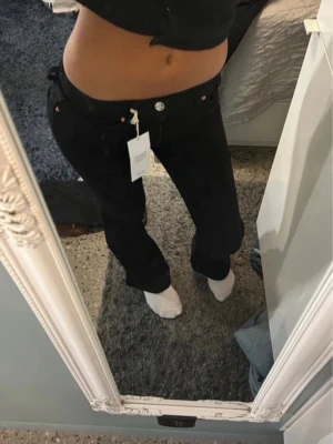 Svarta low waist bootcut jeans 34 - Säljer ett par svarta low waist bootcut jeans från Perfect Jeans i storlek 34. Jeansen har klassisk femficksdesign, silverfärgade detaljer och dragkedja. Materialet är stretchigt och bekvämt, perfekt för dig som gillar en snygg siluett med lite utsvängda ben.