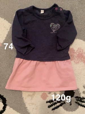 Mörkblå och rosa klänning från Esprit - Supersöt klänning från Esprit med mörkblå överdel och rosa kjol. Långärmad modell med tryckknappar på axeln och ett stilrent hjärta tryckt på bröstet. Perfekt för dig som gillar gulliga detaljer.🌸 Fint använt skick. Storlek 74