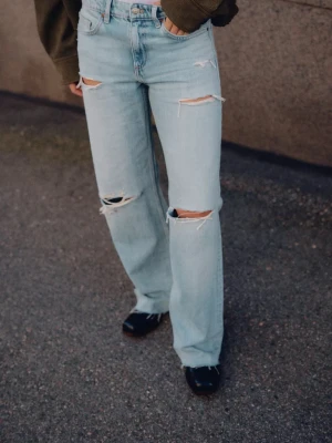 Ljusblå lågmidjade wide leg jeans med slitningar från Zara  - Säljer ett par ljusblå jeans med wide leg och snygga slitningar på både lår och knän. Materialet är jeans i bomull och benen är raka och jeansen är lågmidjade. Helt nya med prislapp kvar! Säljer för att de var för små