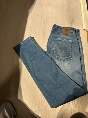 Replay Hyperflex Anbass ljusblå jeans - Säljer ett par Replay Hyperflex Anbass jeans i ljusblå tvätt. Jeansen har klassisk femficksdesign, i slim fit och snygga slitningar. Materialet är stretchigt för extra komfort och passformen är slim. Perfekta för dig som gillar en modern och uppklädd look.