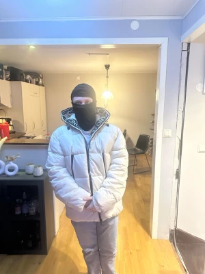Vit pufferjacka från Moncler - Säljer en snygg vit pufferjacka från Moncler med stor huva och dragkedja framtill. Jackan har Moncler-logga på ärmen och tryckt Moncler-text runt huvan. Den är vadderad och har en oversized passform som ger en cool look. Perfekt för kalla dagar.