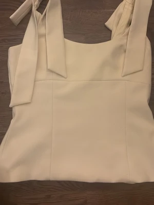 Gul linnetopp med knytband från Zara - Säljer en stilren gul linnetopp från Zara i storlek S. Toppen har breda axelband med knyt som ger en snygg detalj och rak skärning framtill. Materialet känns mjukt och har en lätt glans. Perfekt att matcha med jeans eller kjol.