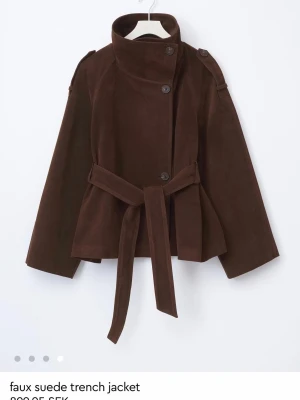 Brun mockajacka från Gina Tricot  - Säljer en superfin brun jacka i mocka från Gina Tricot. Modellen är en kort trench inspirerad jacka med bälte i midjan. Aldrig använd då den tyvärr var för stor för mig, så den är i nyskick o prislappen är kvar. Storlek XS. Perfekt till höst/vår 