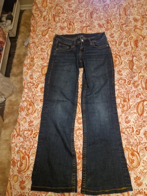 Mörkblå bootcut jeans från HM - Snygga mörkblå jeans från HM, bootcut, storlek 36. Jeansen har klassisk femficksdesign, coola kontrastsömmar och dekorativ broderad bakficka. Tillverkade i slitstarkt denim med en skön passform.