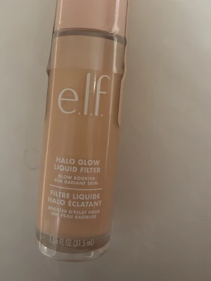 e.l.f. Halo Glow Liquid Filter - Glow booster i flytande form från e.l.f. i en varm beige nyans. Kommer i en stilren glasflaska med ljusrosa lock. Perfekt för att ge huden en strålande finish och naturlig lyster. Färg 2 fair/ light helt ny säljer pga av att den inte kommer till användning 