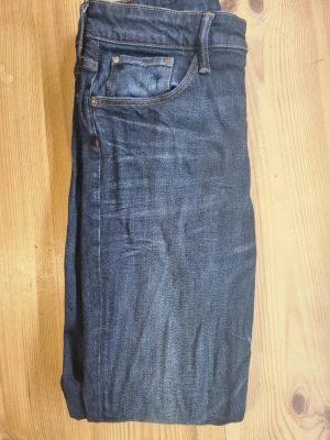 Mörkblå skinny jeans skinny fit - Säljer ett par mörkblå skinny jeans med klassisk femficksdesign och snygga slitningar. Jeansen har skinny fit och är tillverkade i denim med orangea sömmar. Passar perfekt till en avslappnad och trendig stil.