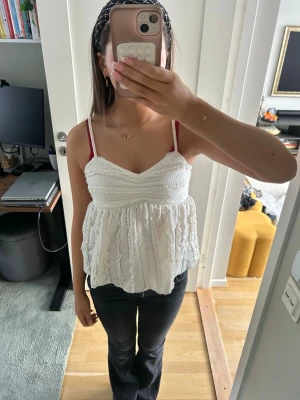Vit spetsdetaljerad linnetopp - Supersöt vit linnetopp med tunna axelband och volangig, luftig passform. Toppen har fina spetsdetaljer och struktur i tyget som ger en romantisk känsla. Perfekt till sommaren och lätt att matcha med jeans eller kjol.