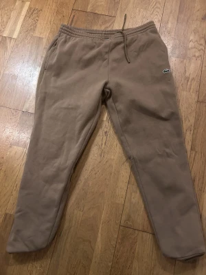 Beige mjukisbyxor från Lacoste XL - Säljer ett par beige mjukisbyxor från Lacoste i slim fit-modell. Köpta på Lacoste butiken (Kastrup, Köpenhamns flygplats) ca 3 år sen storlek XL men passar som M/L