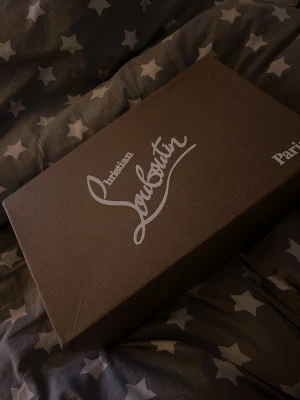 Mörkblå  sneakers från Christian Louboutin - Säljer ett par mörkblå sneakers från Christian Louboutin med snygg rund tå och platt sula. Skorna har snörning och är tillverkade i mocka med mjukt skinnfoder. Kommer med originalkartong, dustbag och äkthetskort. Perfekt för dig som gillar exklusiva märken.
