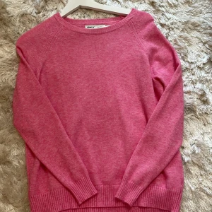 Rosa stickad tröja från ONLY - Mysig rosa stickad tröja från ONLY med rund halsringning och ribbade muddar vid ärmslut och nederkant. Perfekt för lager-på-lager och enkel att matcha med jeans eller kjol. Långärmad och i en mjuk, skön kvalitet.