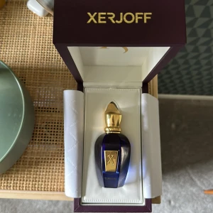 Lyxig Xerjoff parfym i box - Exklusiv parfym från Xerjoff, levereras i elegant originalbox. Perfekt för dig som vill sticka ut med något unikt och lyxigt. Flaskan har en modern design med gulddetaljer och djupblå färg. Flaskan är 50 ml och är full