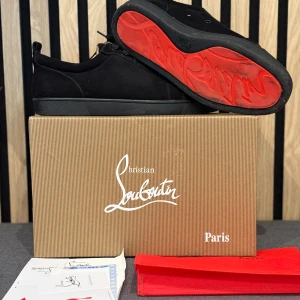 Christian Louboutin svarta sneakers mocka. INTRESSE KOLL!! - Svarta sneakers från Christian Louboutin i lyxig mocka med klassisk röd sula och snygga svarta skosnören. Skorna har rund tå och platt sula, samt diskret branding på innersulan. Perfekta för dig som vill ha en stilren och exklusiv look.