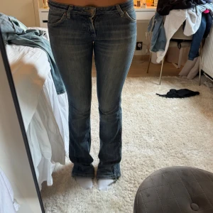 Wrangler  bootcut jeans - Säljer ett par klassiska blå bootcut jeans från Wrangler, modell Megan. Jeansen har snyggt slitna detaljer, fem fickor och ikonisk W-söm på bakfickan. Tillverkade i bomull med en skön passform och låg midja. Perfekta till sneakers eller boots.