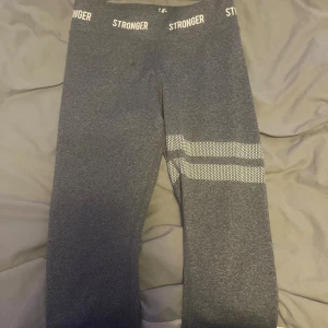 Grå leggings från Stronger - Mörkgrå leggings från Stronger. Perfekta för träning och tillverkade i stretchigt syntetmaterial.