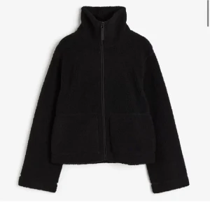 Svart teddyjacka från hm - Mysig svart teddyjacka med hög krage och hel dragkedja framtill. Jackan har två stora fickor och är perfekt för kyliga dagar. Den har en enkel och stilren design som passar till det mesta.
