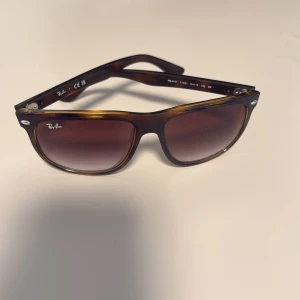 Rayban boyfriend - Snygga boyfriends från Ray-Ban i brun transparent plast med klassisk fyrkantig form. Glasen är tonade i brunt och bågarna har diskreta silvriga detaljer vid fronten. Perfekta för att lyfta din stil under soliga dagar. pris kan diskuteras