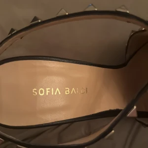 Svarta högklackade skor  från Sofia Baldi/buty na wysokim obcasie - Svarta hög klack  i skinn från Sofia Baldi med spetsig tå och hög klack. Skorna har coola silverfärgade nitar längs remmarna som ger en edgy vibe. Perfekta för dig som vill sticka ut med en stilren men tuff look. Ny och oanvänd 