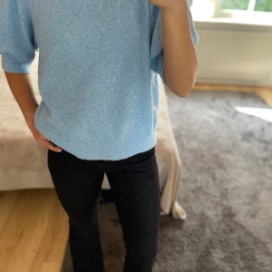 Ljusblå stickad tröja från Vero Moda - Superfin ljusblå stickad tröja från Vero Moda med korta puffärmar och rund halsringning. Tröjan har en mjuk och mysig känsla, perfekt för lager-på-lager och chill dagar. Ribbstickade muddar vid ärmslut och nederkant ger en snygg finish.