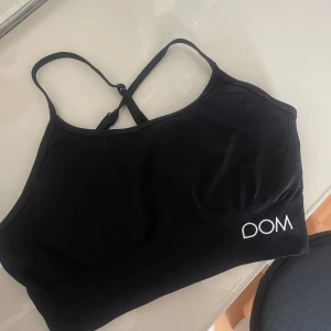 Svart linnetopp från Drop of Mindfulness - Säljer en svart linnetopp från Drop of Mindfulness med smala axelband och brottarrygg. Toppen har en stilren design med logga både fram och bak. Perfekt för träning eller chill dagar. Materialet är mjukt och stretchigt för bästa komfort.