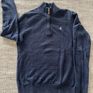 Mörkblå halvziptröja från Morris XS - Mörkblå stickad tröja från Morris med ribbad hög krage och snygg half zip-dragkedja med läderdetalj. Liten broderad logga på bröstet. Perfekt för lager-på-lager och chill stil.