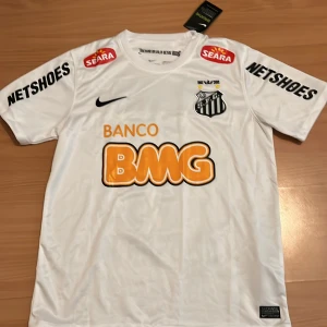 Vit Santos Neymar Jr Nike fotbollströja S - Santos officiella fotbollströja från Nike med Neymar Jr och nummer 11 på ryggen. Tröjan är vit med svarta och orangea tryck, korta ärmar och tillverkad i Dri-Fit material för bästa komfort. Klubbmärke och flera sponsorer på bröst och ärmar. Pris kan diskuteras vid snabb och smidig affär😊😊